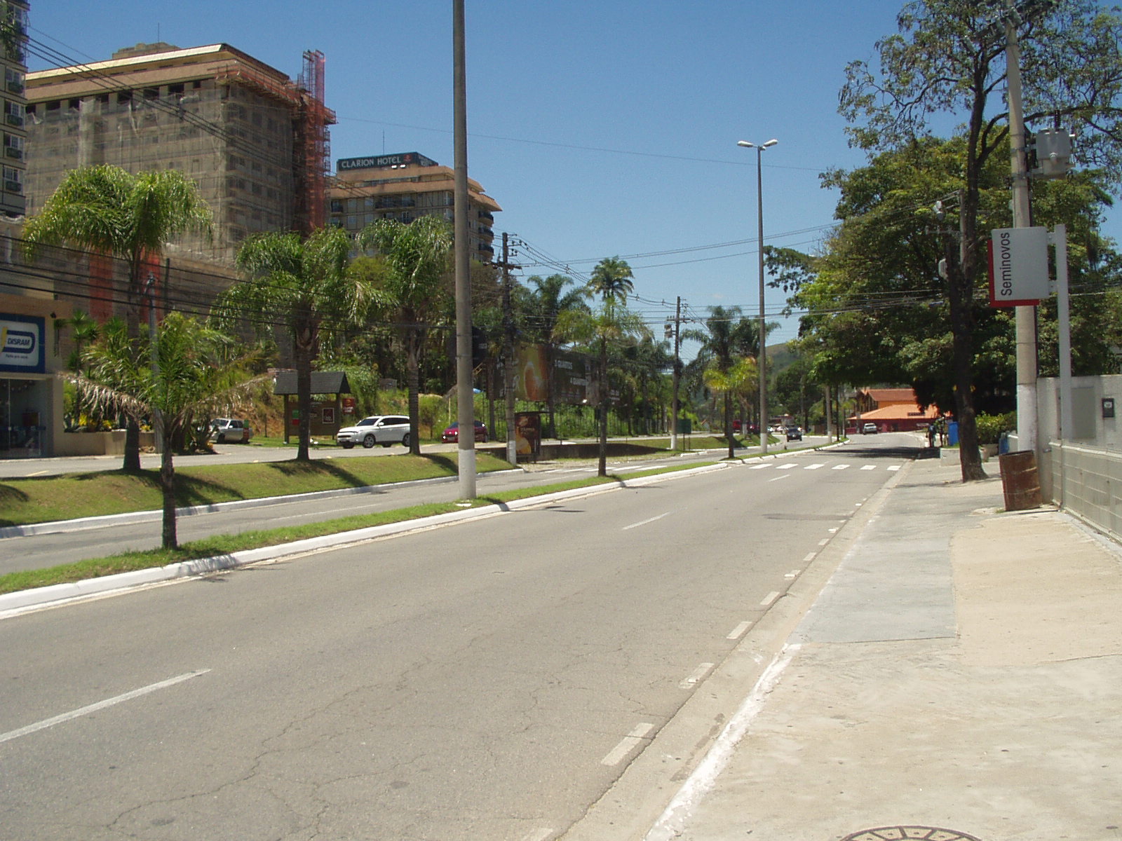 Trecho da Estrada União e Indústria em Itaipava, com edifícios, veículos, calçadas e arborização.
