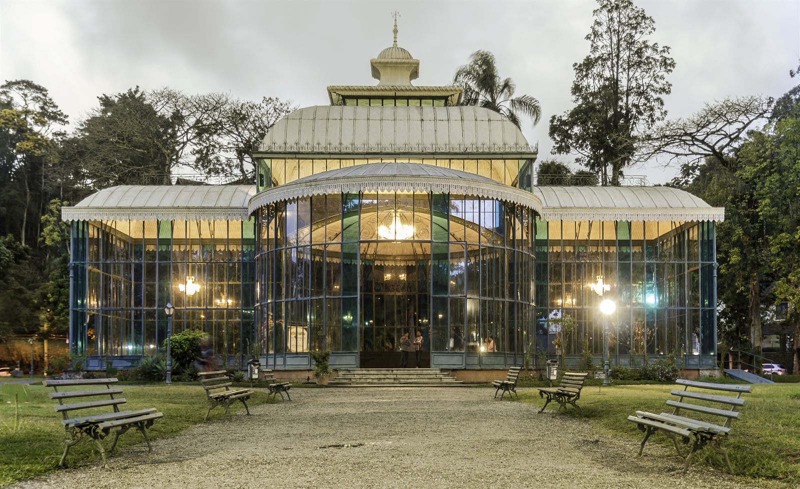Fachada iluminada do Palácio de Cristal, em Petrópolis, vista de frente ao entardecer.